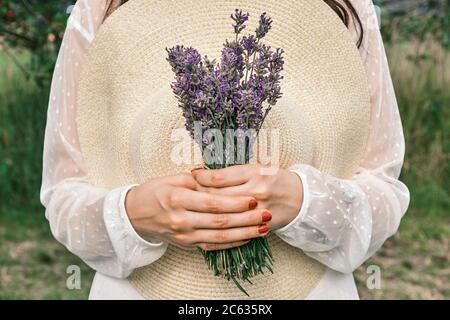 Frau mit Hut und Lavendelstrauß in der Hand. Provenzalischer Landstil Stockfoto