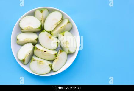 Frische grüne Apfelscheiben auf weißem Teller auf blauem Hintergrund. Draufsicht mit Kopierbereich Stockfoto
