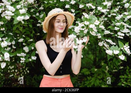 Junge Frau in einem Sommerhut geht unter der Blüte Bäume Stockfoto