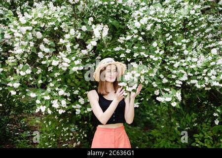 Junge Frau in einem Sommerhut geht unter der Blüte Bäume Stockfoto