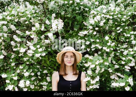 Junge Frau in einem Sommerhut geht unter der Blüte Bäume Stockfoto