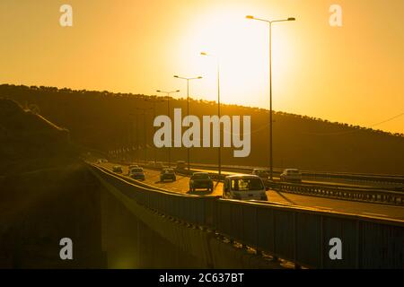 Ankara/Türkei-Juli 04 2020: Autos fahren bei Sonnenuntergang über der Autobahnbrücke über dem Dorf. Verkehr auf der Umgehungsstraße über der Stadt. Stockfoto