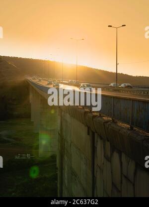 Ankara/Türkei-Juli 04 2020: Autos fahren bei Sonnenuntergang über der Autobahnbrücke über dem Dorf. Verkehr auf der Umgehungsstraße über der Stadt. Stockfoto