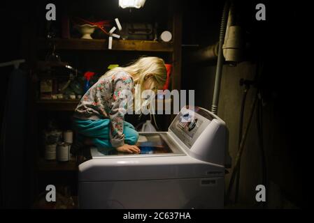 Kleines Mädchen, das auf der Waschmaschine sitzt Stockfoto