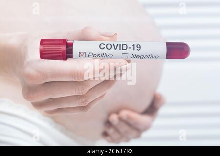 Schwangere Frau mit biologischem Schlauch mit positivem Ergebnis auf COVID-19. Coronavirus während der Schwangerschaft. Nahaufnahme. Stockfoto