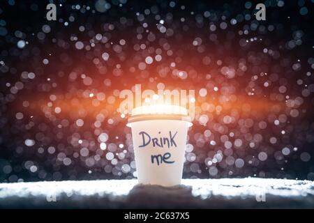Große Papiertasse mit Tee oder Kaffee auf fallendem Schnee in der Nacht Stockfoto
