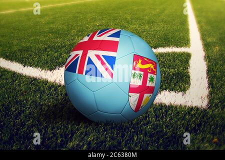 Fidschi-Flagge auf Ball in Eckkick-Position, Fußballfeld Hintergrund. Fußball-Nationalthema auf grünem Gras. Stockfoto