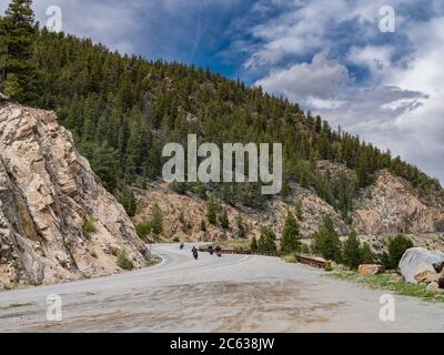 Gruppe von Motorrädern auf gekrümmter Autobahn durch felsige Berge, Colorado, USA Stockfoto