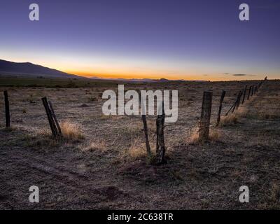 Alte Stacheldrahtzaun bei Sonnenuntergang mit Bergen, Westcliffe, Colorado USAS Stockfoto