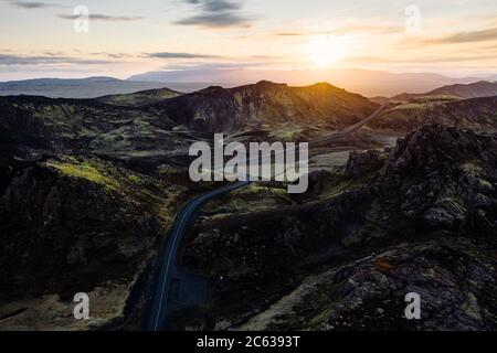 Drone Blick auf kurvenreiche Autobahn in felsigen Tal gegen erstaunliche Sonnenuntergang in Nesjavellir Reykjavik Island Stockfoto