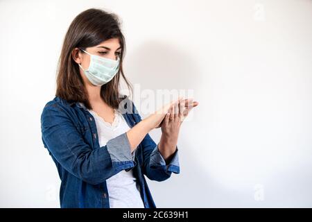Frau mit medizinischer Schutzmaske, die antiseptisch ansetzt, um ihre Hände zu desinfizieren Stockfoto