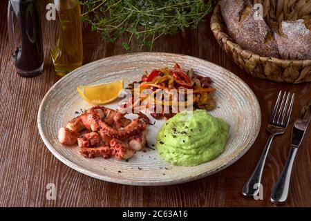 Gegrillter Oktopus mit Kartoffelpüree und Gemüsesaute aus nächster Nähe. Die traditionelle mediterrane Küche. Stockfoto