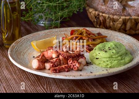 Gegrillter Oktopus mit Kartoffelpüree und Gemüsesaute aus nächster Nähe. Die traditionelle mediterrane Küche. Stockfoto