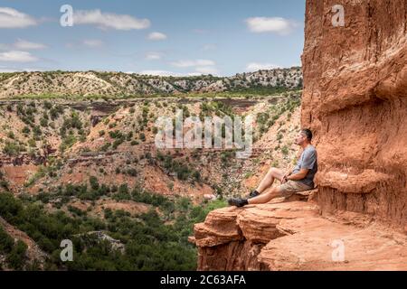 Mann, der am Rande des Lighthouse Rock sitzt, Palo Duro Canyin State Park, Texas Stockfoto