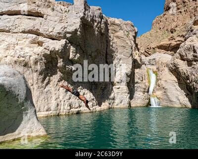 Junger Mann, der in den natürlichen Schwimmbädern des Wadi Bani Khalid, Sultanat von Oman, taucht. Stockfoto