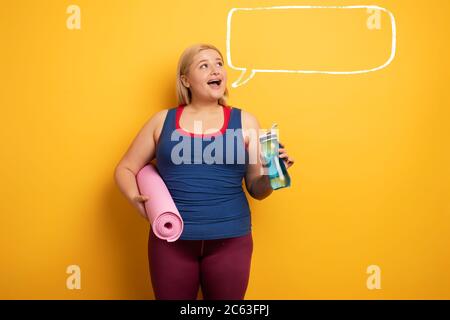 Fat Mädchen tut Fitness-Studio zu Hause. Zufriedene Ausdruck. Gelber Hintergrund Stockfoto