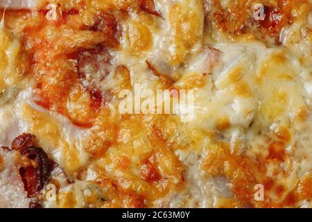 Pizza mit Käse, Sauce und Schinken, Speck, Salami auf grauem dunklen Hintergrund Stockfoto