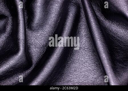 Schwarze Kunsthaut Nahaufnahme. Textilmaterial, schlampige Falten. Schwarzer Lederhintergrund. Stockfoto
