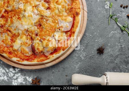 Pizza mit Käse, Sauce und Schinken, Speck, Salami auf grauem dunklen Hintergrund Stockfoto