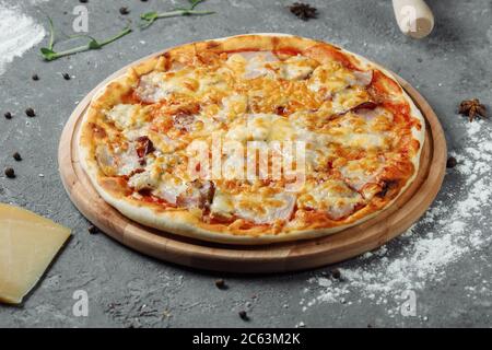 Pizza mit Käse, Sauce und Schinken, Speck, Salami auf grauem dunklen Hintergrund Stockfoto
