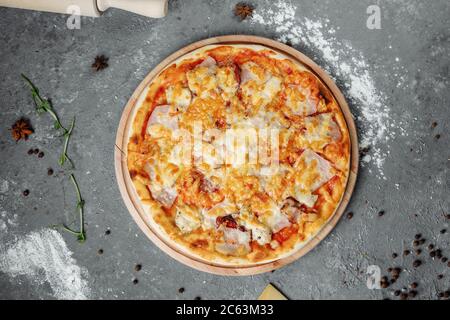 Pizza mit Käse, Sauce und Schinken, Speck, Salami auf grauem dunklen Hintergrund Stockfoto
