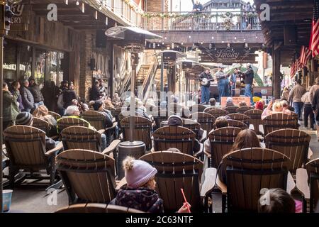 Die Leute sitzen und beobachten eine Gruppe von Musikern Hillbilly-Musik auf der Bühne im Ole Smoky Moonshine Einkaufszentrum in Gatlinburg, Tennessee, USA Stockfoto