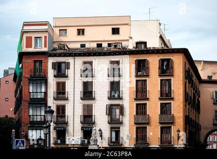 Flachgewinkeltes Äußeres eines alten Steinhauses mit bunten Wänden und Balkonen an der Straße von Madrid Stockfoto