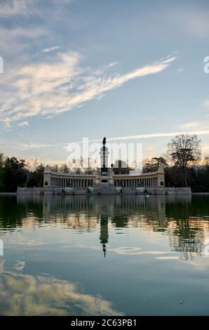 Landschaftlich schöne Aussicht auf altertüm Denkmal von König Alfonso XII vor dem Teich mit Reflexion der erstaunlichen Sonnenuntergang Stockfoto