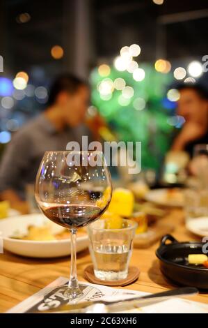 Bangkok / Thailand - Dez 31 2018 : in einem Restaurant wurden ein Glas Wein und ein Glas Wasser auf den Tisch gelegt, verschwommener Hintergrund ist eine Gruppe von Freunden Stockfoto