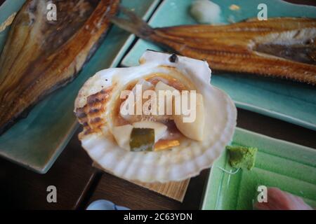 Jakobsmuscheln oder Hotat auf der Schale platziert und über einem kleinen Ofen gegrillt ist ein japanisches Essen. Stockfoto