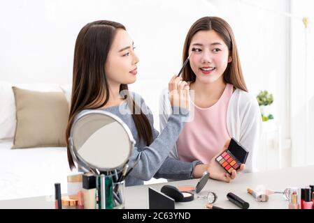 Schöne asiatische Frau Schönheit vlogger tun kosmetische Make-up Demonstration mit ihrem Freund zu Hause Stockfoto