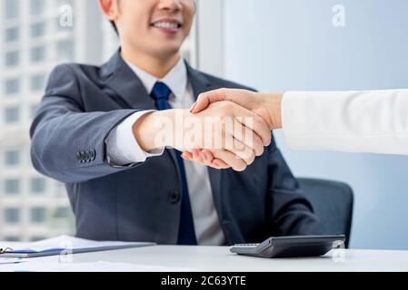 Junger Geschäftsmann, der mit einer Geschäftsfrau im Besprechungsraum im Büro Handshake macht Stockfoto