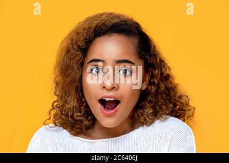 Überrascht gemischte afrikanische Frau keuchend isoliert auf gelbem Hintergrund Stockfoto