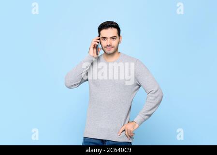 Portrait von handsosme kaukasischen Mann auf Handy in isolierten hellblauen Studio Background anrufen Stockfoto