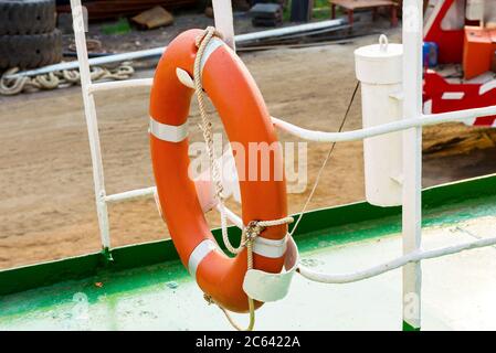 Orange Rettungsboje, die in einem Handlauf auf dem Schiff hängt Stockfoto