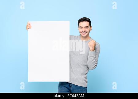 Schöner kaukasischer Mann zeigt leere weiße Papiertafel mit Faust Anhebung auf hellblau isolierten Hintergrund Stockfoto