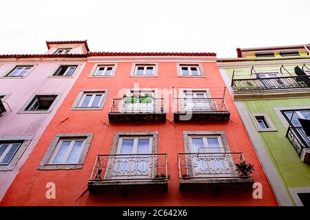 Pinke, orange und gelb-grüne Apartmenthäuser mit eisernen Balkonen in Lissabon, Portugal. Stockfoto