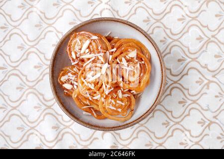 HAUSGEMACHTE JALEBI MIT MANDELFLOCKEN Stockfoto