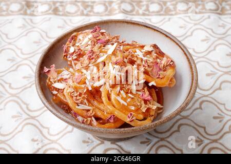 SELBSTGEMACHTER JALEBI MIT MANDELFLOCKEN UND ROSENBLÄTTERN Stockfoto