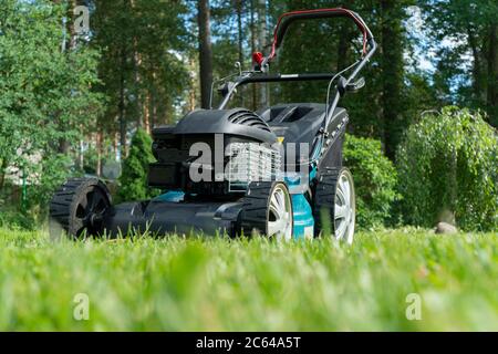 Rasenmähen. Rasenmäher auf grünem Gras. Rasenmäher. Mähen Gärtner Pflege Arbeitswerkzeug Nahaufnahme. Sonniger Tag. Stockfoto