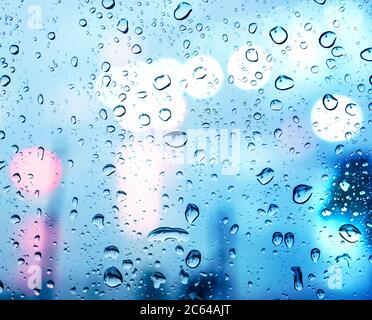 Wassertropfen auf Glasfenster mit Bokeh-Lampen Stockfoto