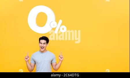 Junge gut aussehende asiatische Mann zeigt bis zu 0% auf gelbem Hintergrund mit Kopieplatz für keine Zinsen Ratenzahlung Konzept Stockfoto