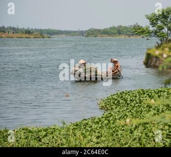 Zwei Einheimische rudern über den mächtigen Thu Bon Fluss im ländlichen Vietnam. Stockfoto