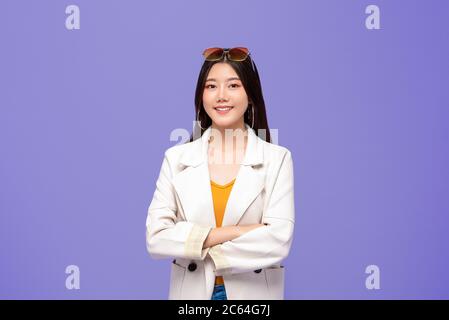 Porträt von jungen ziemlich lächelnden asiatischen Frau in smart Freizeitkleidung Kreuzung Arme auf bunten lila Hintergrund Stockfoto