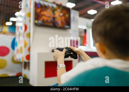 Boy spielt eine Spielkonsole im Entertainment Center Stockfoto