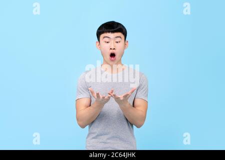 Fun Porträt von erstaunt jungen asiatischen Mann Blick auf beide Hände mit offenem Mund in isolierten Studio blauen Hintergrund Stockfoto