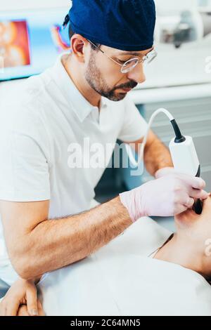 Zahnarzt mit Brille behandelt die Zähne zum Patienten - Installation von Füllungen Stockfoto