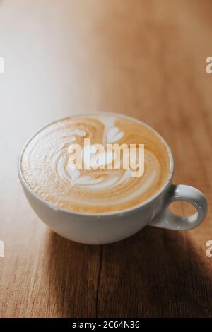 Die Kunst, auf Milchschaum zu zeichnen, wenn man Latte und Cappuccino in einer weißen Tasse auf einem Bartisch zubereitet Stockfoto