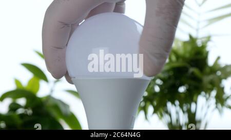 Die Hand eines Elektrikers dreht eine LED-Glühlampe in der Steckdose, um das Licht auszuschalten Stockfoto