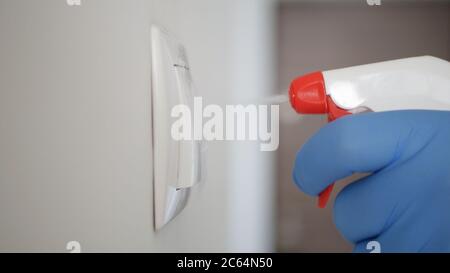 Mann trägt Schutzhandschuhe Reinigung und Desinfektion Licht Schalter aus dem Büroraum mit Desinfektionsmittel gegen Covid-19 Viren Stockfoto